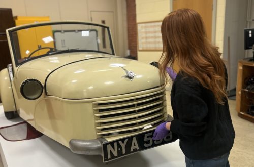 Person wearing gloves touching a car model inside a conservation studio