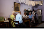 Four people sit around a table in a reconstructed Victorian room at the People's History Museum.