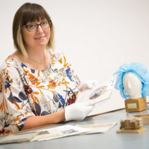 Claire Sleighholm wearing white gloves handling a photograph in a museum collection