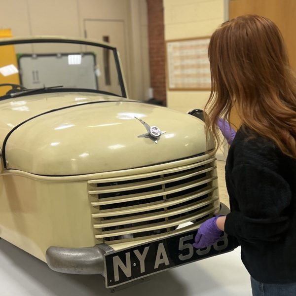 Person wearing gloves touching a car model inside a conservation studio