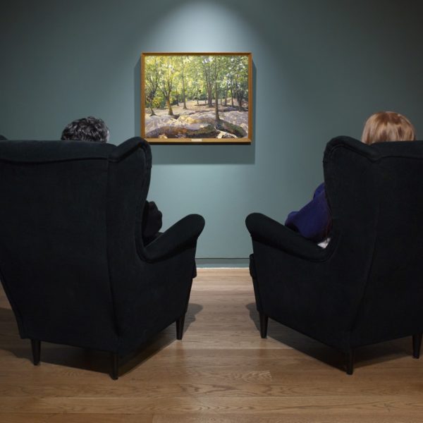 Two people sat on armchairs looking at a framed painting on a blue gallery wall